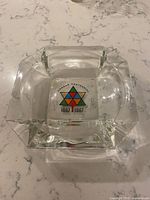Top view of a clear square glass ashtray with the Canada Centennial 1867-1967 colorful star logo in the center.
