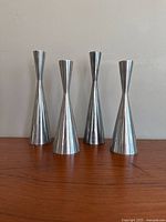 Front view of all four aluminum candle holders arranged in a row, showing slim and tapered design.
