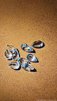 Seven pear cut sky blue topaz gemstones displayed on a textured surface under lighting showing clarity and color.
