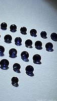 Multiple small round natural royal blue sapphires laid out individually for display, showing the deep blue color and facets.