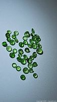 Close-up photo of loose natural Tsavorite garnet gemstones showing rich green color and round faceted cuts.