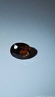 Oval cut orange tourmaline gemstone, showing facets and coloration.
