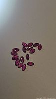Photo showing 17 marquise-shaped natural rubies with deep red color, untreated and clear, laid out on flat surface.
