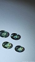 Four oval cut tri-colored sapphires laid on a flat surface, showing their color variation and clarity.