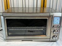 Front view of stainless steel toaster oven showing door, handle and digital display