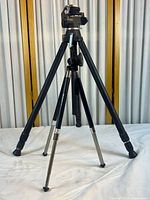 Front view of the black and silver metal and plastic tripod fully extended on a white surface