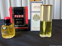 Two parfum spray bottles with their original boxes: Estée Lauder White Linen and Yves Saint Laurent Paris Eau de Toilette. Displayed on black surface.