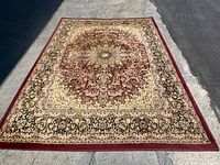 Full view of rectangular red area rug with central medallion and floral geometric patterns.