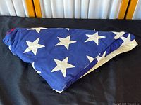 Triangular folded American flag showing large white stars on dark blue background.