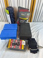 All items in the lot arranged on a cloth surface including yoga blocks, Century gloves in packaging, Nike gloves, Everlast gloves in mesh bag, and a foam roller.