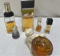 Six vintage perfume bottles arranged including ceramic cat with perfume bottle and various glass bottles of different shapes and sizes