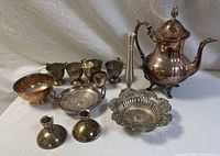 Full view of the silverplate collection arranged showing the teapot, goblets, bowls, trays, candlestick holders, and decorative pieces.