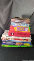 Stack of board game boxes including Checkers, Pictionary, Taboo, Scattergories, Battleship, Carriers, and Bumpershot