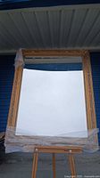 Framed wall mirror with gold finish and beveled glass photographed full view on easel.