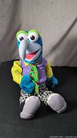 Front and side view of Jim Henson's Muppets Gonzo plush doll seated against gray backdrop with soft lighting.