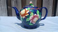 Side view of Maling ceramic teapot showing hand-painted orange and pink flowers with green leaves on a blue base.