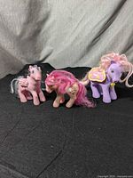 Lot of three My Little Pony figures from Hasbro G1 and G3 styles, displayed on black fabric