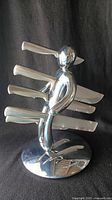 Front view of chrome humanoid block holding five knives