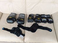 All items displayed together including gloves and wrist guards on beige couch.