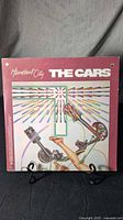 Front cover of the Heartbeat City album by The Cars showing full artwork and title. Vinyl LP in a maroon gatefold cover.