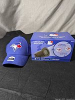 Toronto Blue Jays men's cap next to boxed LED galaxy spotlight on dark surface