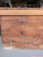 Close-up of front side showing the oval Quebec stamp with '56 lbs net' capacity marking and faint partial brand markings.