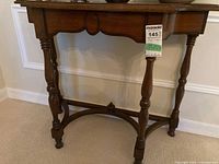 Front view of wood demi-lune console table showing the curved apron and legs.