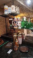 Shelf display showing multiple beer mugs and steins including Expo 86 stein, Quebec mug, decorative ceramic steins, glass bottles in green, and smaller metal mug containers.