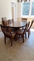 Oak oval dining table with leaf extension and six matching oak chairs in dining room.