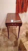 End table with drop leaves closed showing top surface and front drawer.