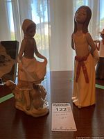 Photo showing two Lladro porcelain figurines on a table near window, highlighting size and details.