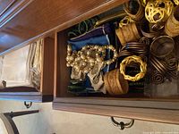 Drawer containing folded cloth napkins accompanied by various napkin rings, showing different textures and styles.