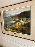 Full view of framed landscape painting showing coastal scene, cottage and hills