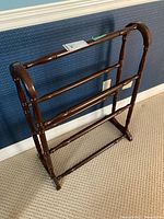 Full view of the wooden quilt rack showing the three horizontal rails and curved top edges.