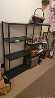 Side angle view of the black metal utility shelf with items placed on surrounding shelves.