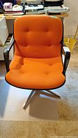 Front view of the Steelcase vintage chair showing tufted orange seat and backrest with metal armrests and swivel base.