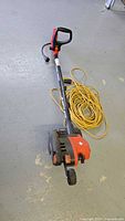 Full view of Black & Decker Edge Hog electric trimmer on floor with extension cord coiled beside it.