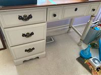 Front left side view of Vilas desk showing drawer handles and part of the natural wood top