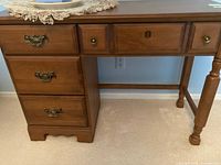Front and side view of Vilas maple desk showing drawers and turned legs.