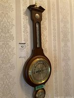 Full view of the wooden framed vintage weather station showing the barometer, thermometer, and hygrometer mounted on a wall.