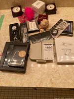 Wide view of the lot showing clocks, watch, purse holder, frame, calculator, mirror and small boxes