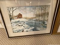 Framed watercolour painting showing a snow-covered river landscape with a barn and trees.