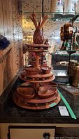 Full view of the wooden multi-tier serving stand with bowls and pineapple-shaped top finial on a countertop.