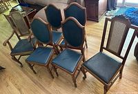 Front view of six wooden chairs: four side chairs with blue upholstered seats and carved backs, two armchairs with cane backs and blue upholstered seats.