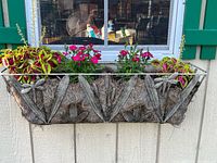 One assembled metal dragonfly window box mounted with a coco liner, filled with decorative plants.