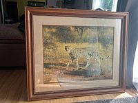 Framed photo showing leopard in natural wildlife setting inside a brown wooden frame with cream matting.
