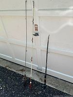 Full view showing three rods including the Garcia rod in center with white upper section and cork handle.