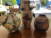 Photo showing all three pottery vases on a wooden surface with outdoor background.
