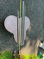 Four metal rods laid on a wooden surface outdoors with a measuring tape showing the length of one rod.