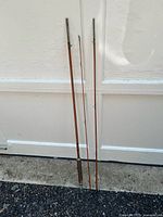 Photo showing the three separate pieces of the bamboo fishing rod placed against a white wall.